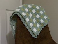 a green and white crocheted afghan on a chair